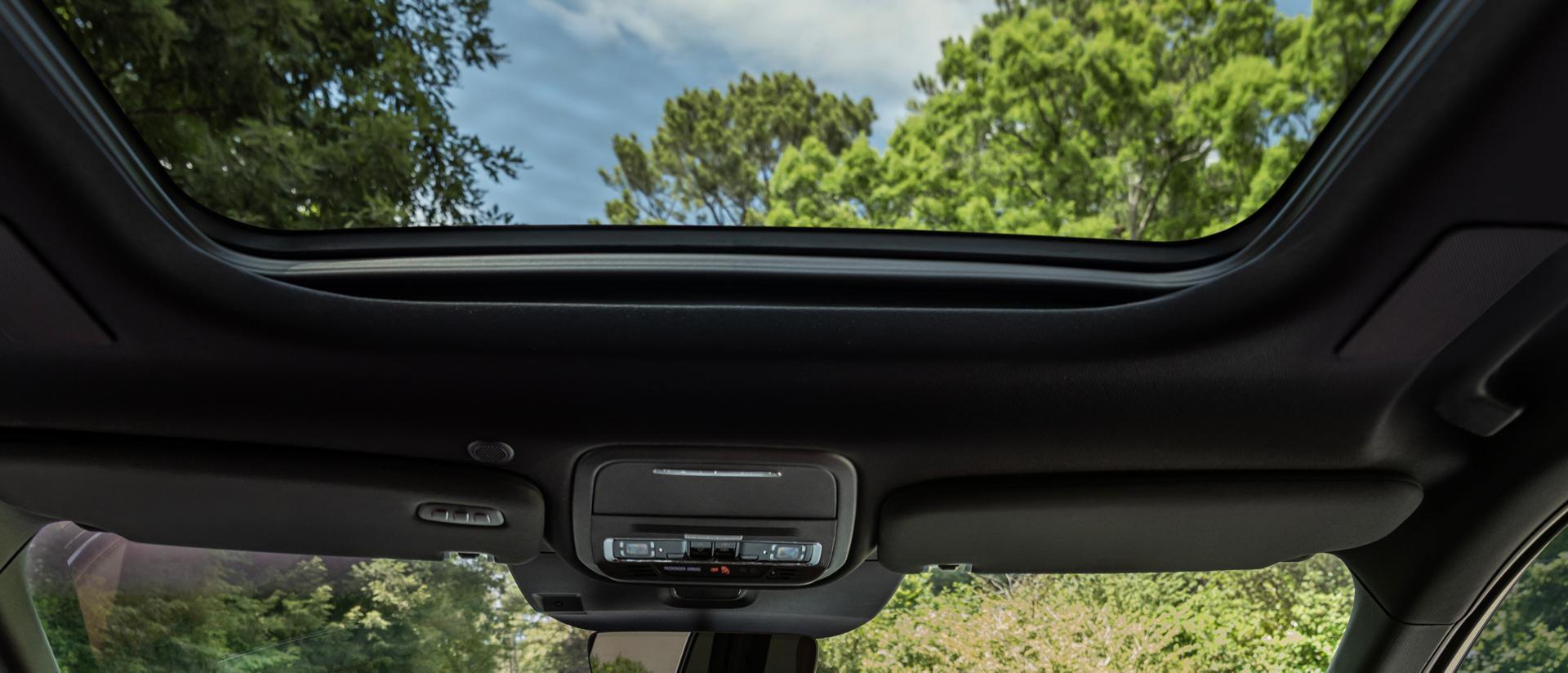 A lush forest scene is shown the the front windshield and panoramic Vista Roof® of a 2027 Lincoln Aviator®