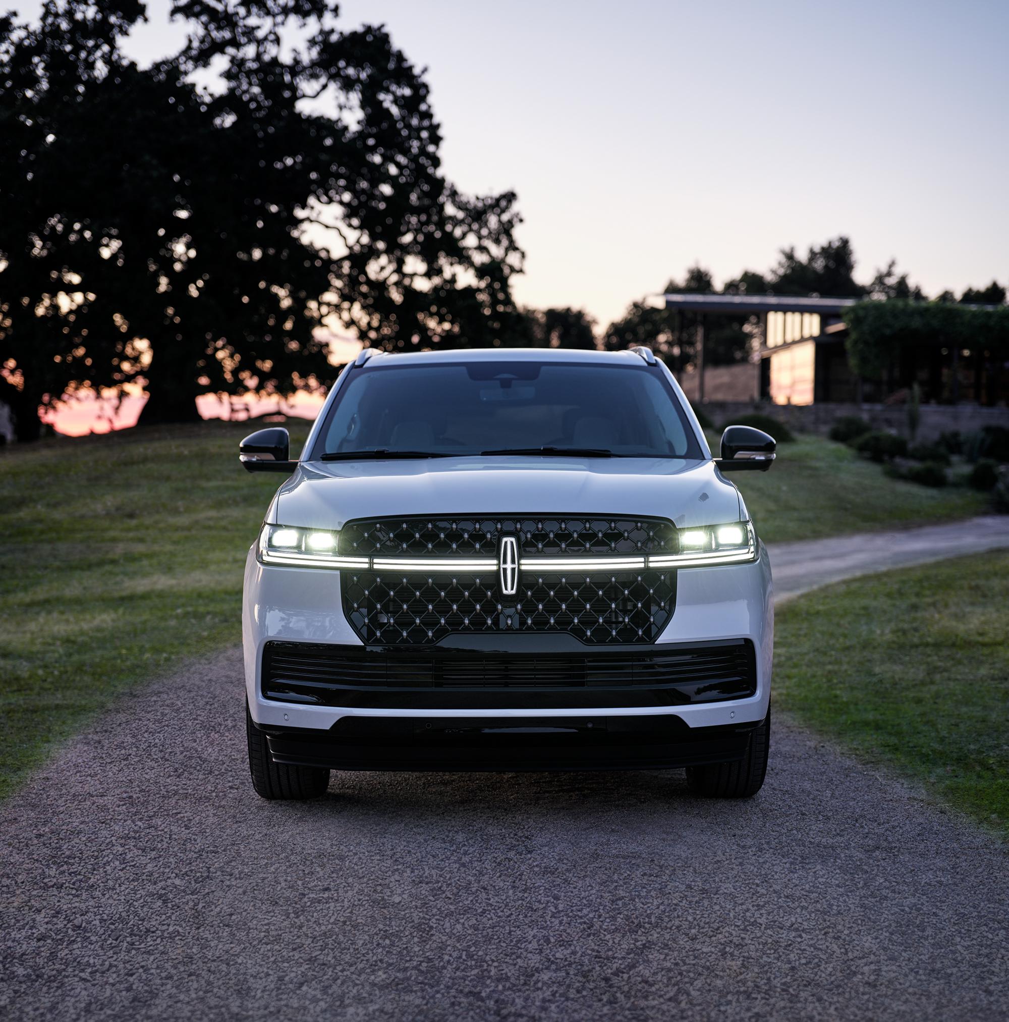 The front of a 2027 Lincoln Navigator® SUV with headlamps and Lincoln Star illuminated at dusk