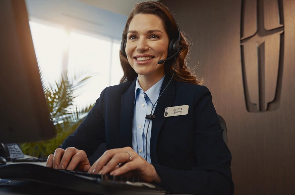 A lincoln support staff with a headset and smiling.