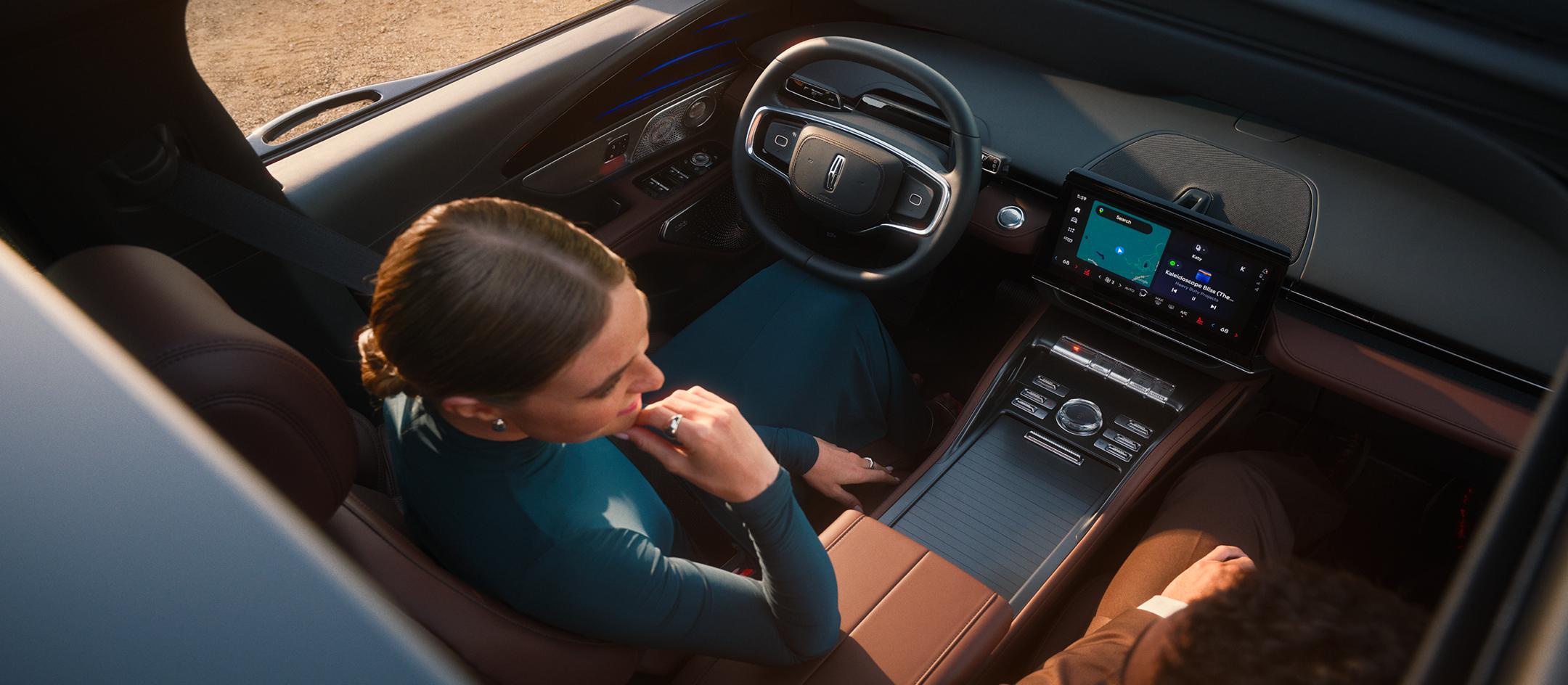 A woman and man sitting inside a Lincoln vehicle.