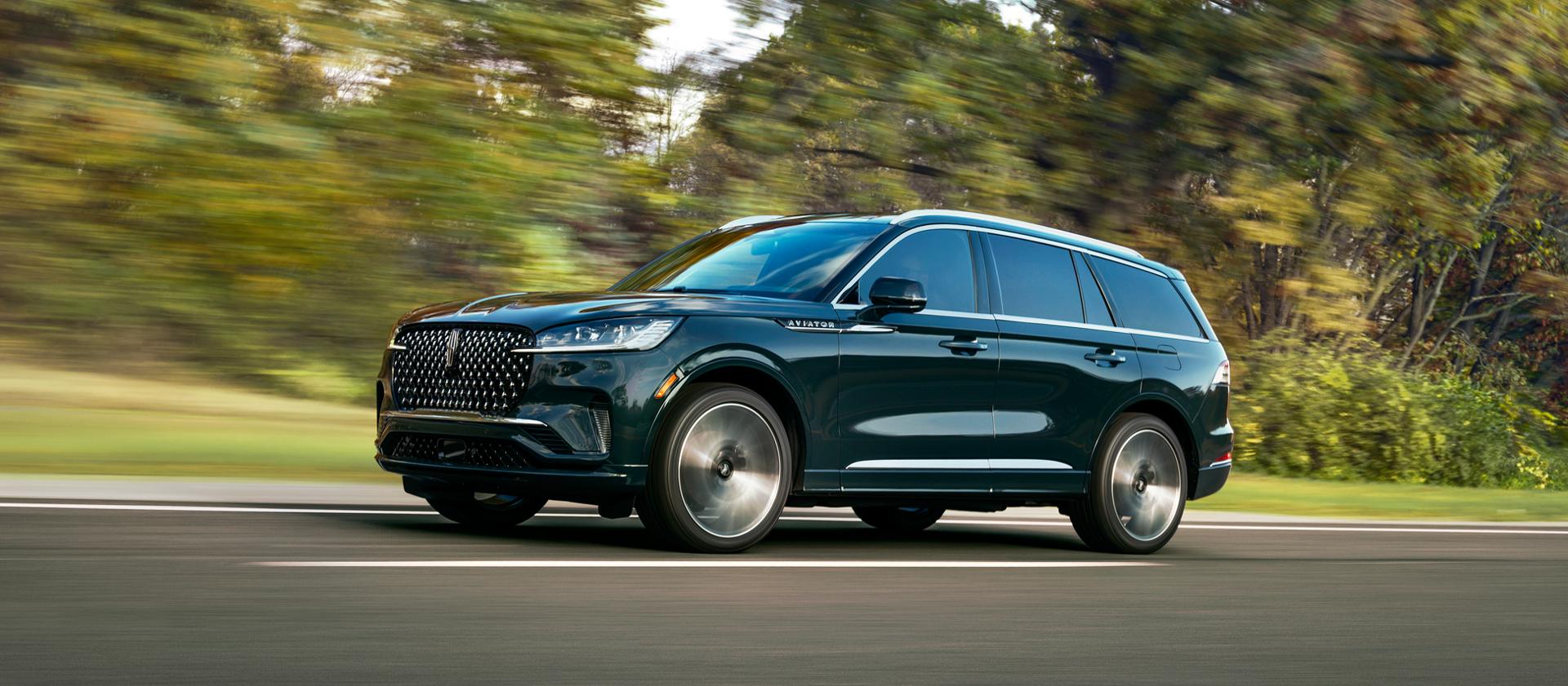 A 2027 Lincoln Aviator® Black Label® is being driven in a lush countryside