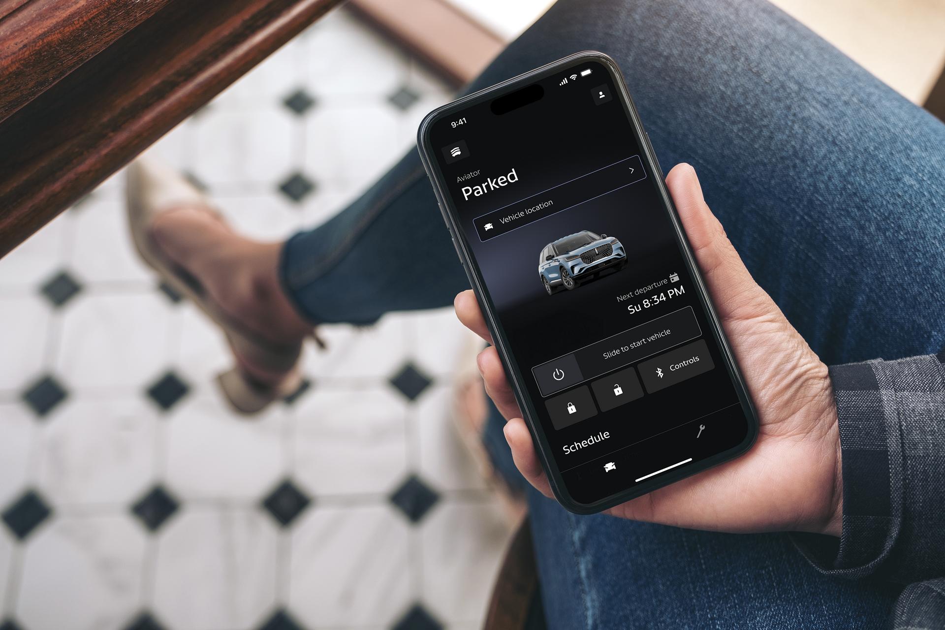 A person holding a phone with the Lincoln app opened on it.