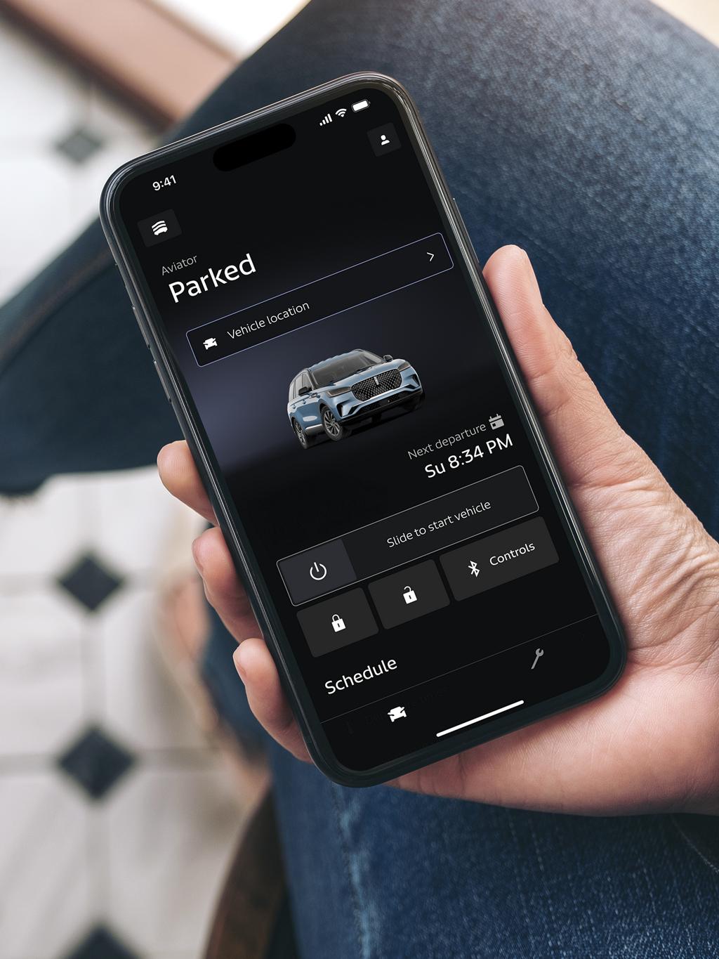 A person holding a phone with the Lincoln app opened on it.