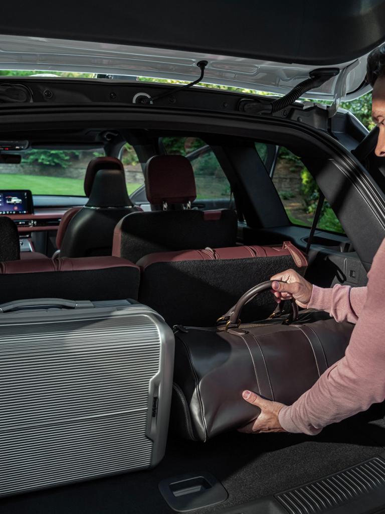 A person loads a leather bag into the rear cargo area of a 2026 Lincoln Aviator