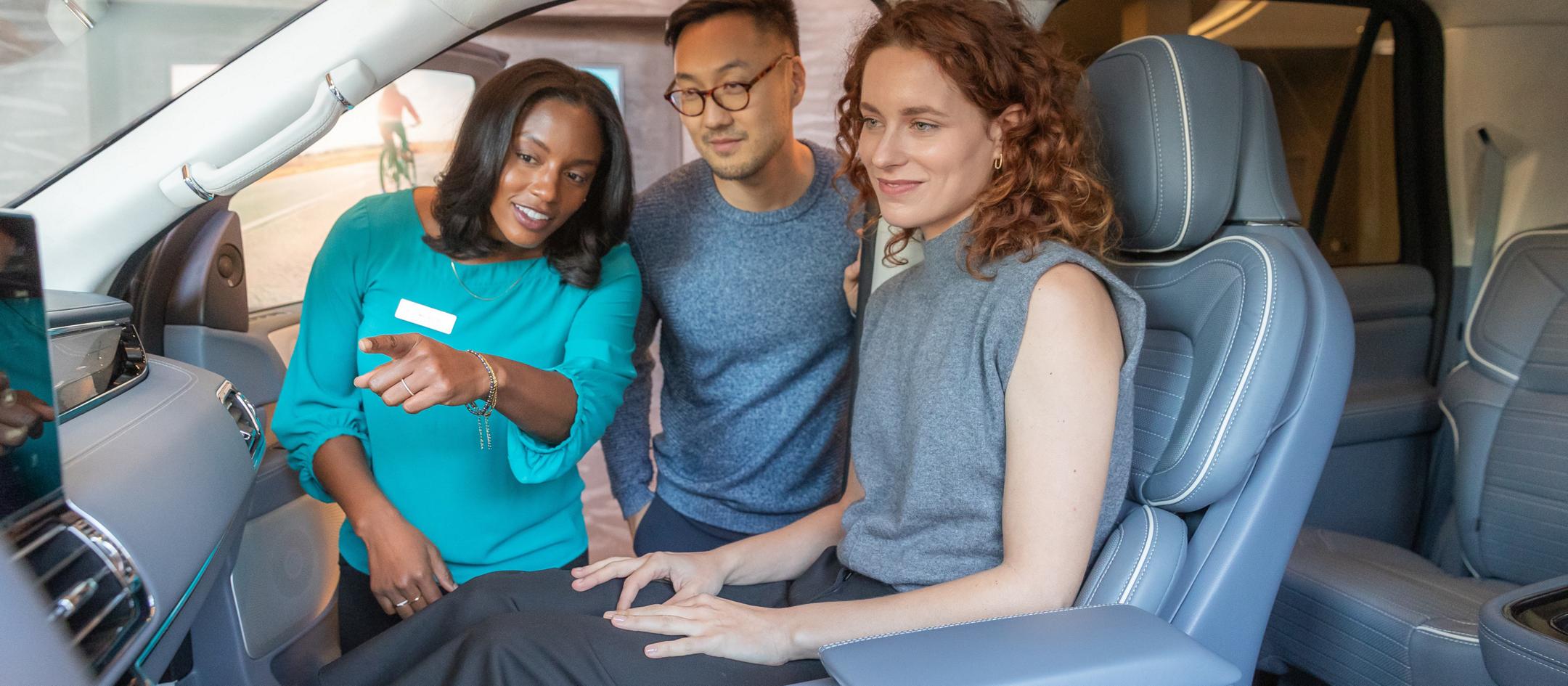 Customers exploring a Lincoln vehicle interior with a sales associate.