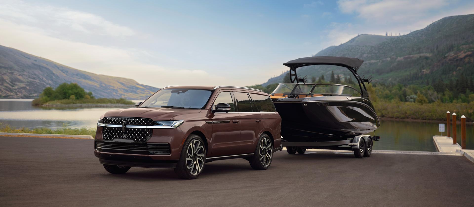 A 2027 Lincoln Navigator® Black Label™ model has a boat hitched up by the water
