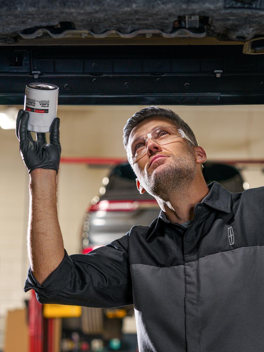 Lincoln technician working on a vehicle from underneath.