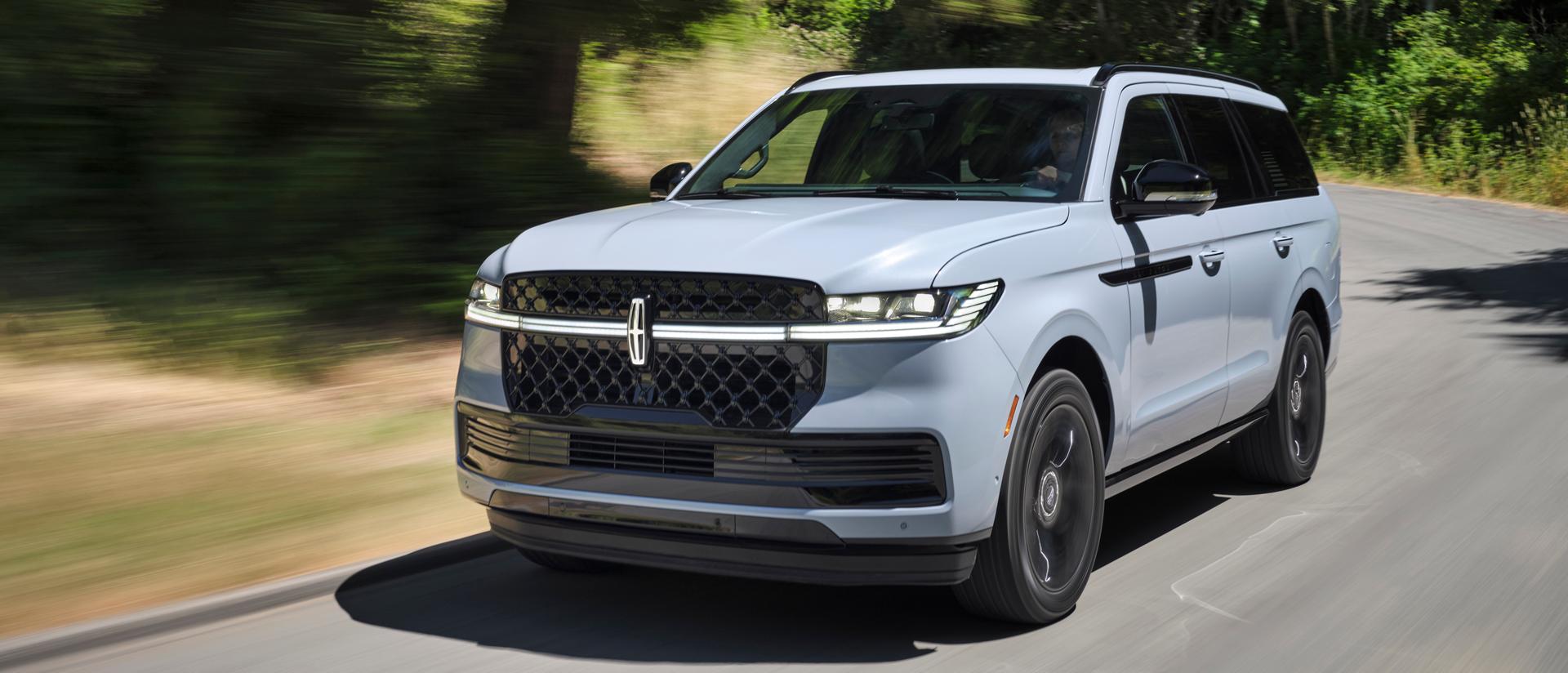 A 2026 Lincoln Navigator® SUV is being driven on a country road