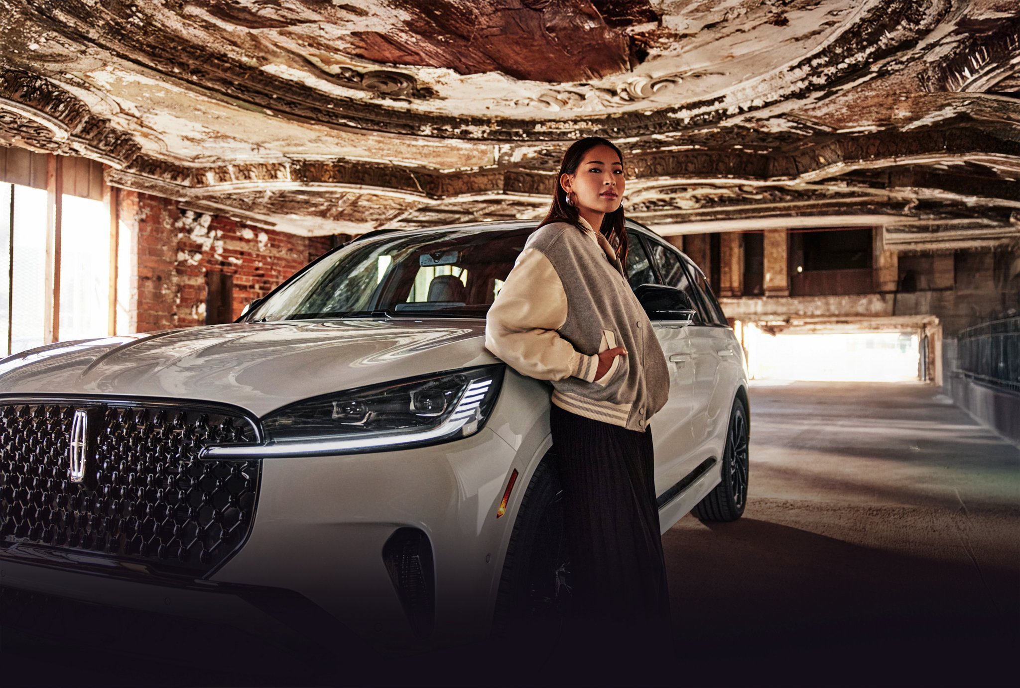 A woman standing in front of a Lincoln vehicle.
