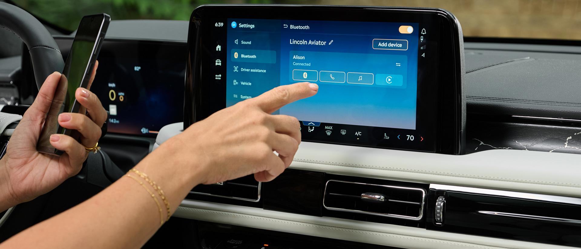 A hand reaches out to interact with the centre touchscreen of a 2027 Lincoln Aviator®