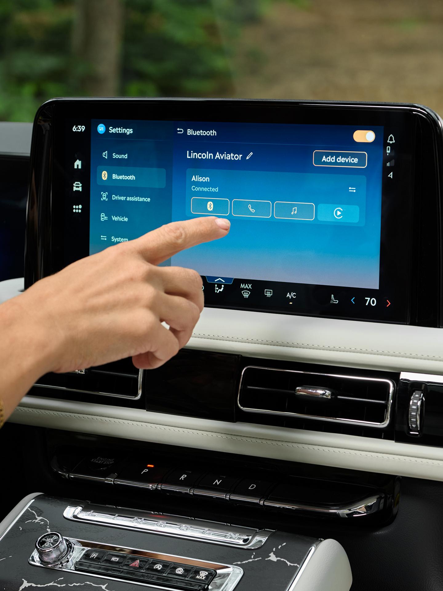 A hand reaches out to interact with the centre touchscreen of a 2027 Lincoln Aviator®