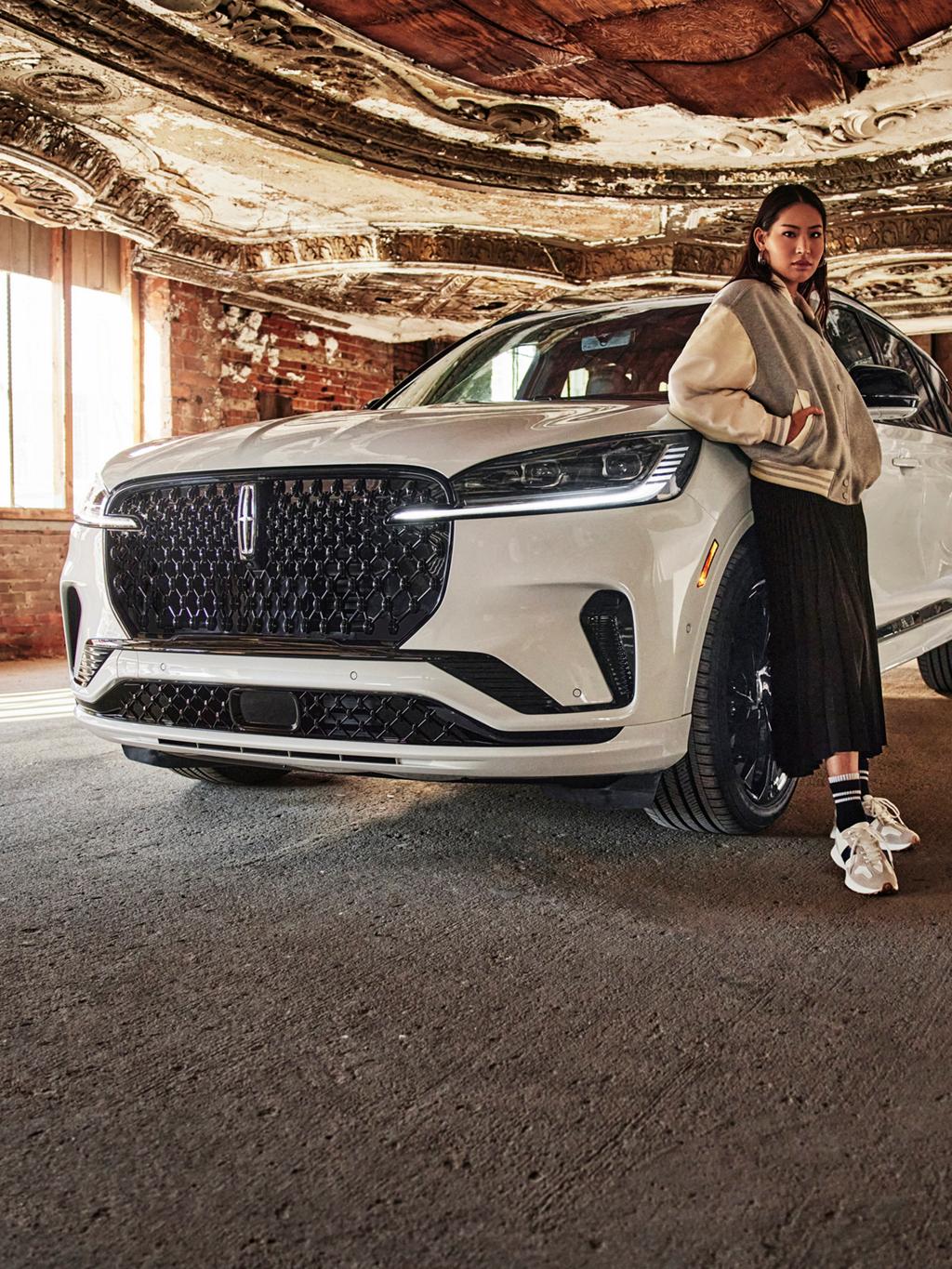 A woman standing in front of a Lincoln vehicle.