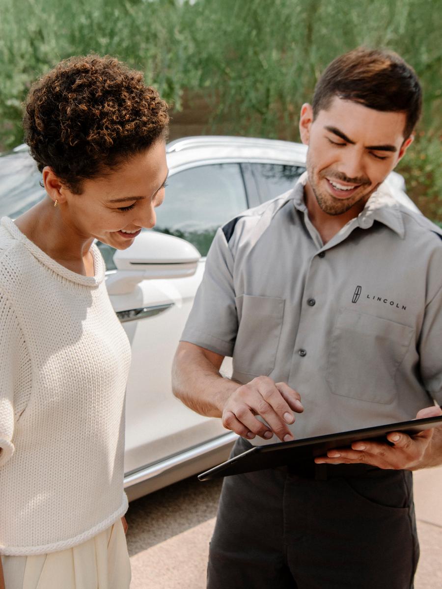 Lincoln service advisor holding a tablet and showing something to a customer.