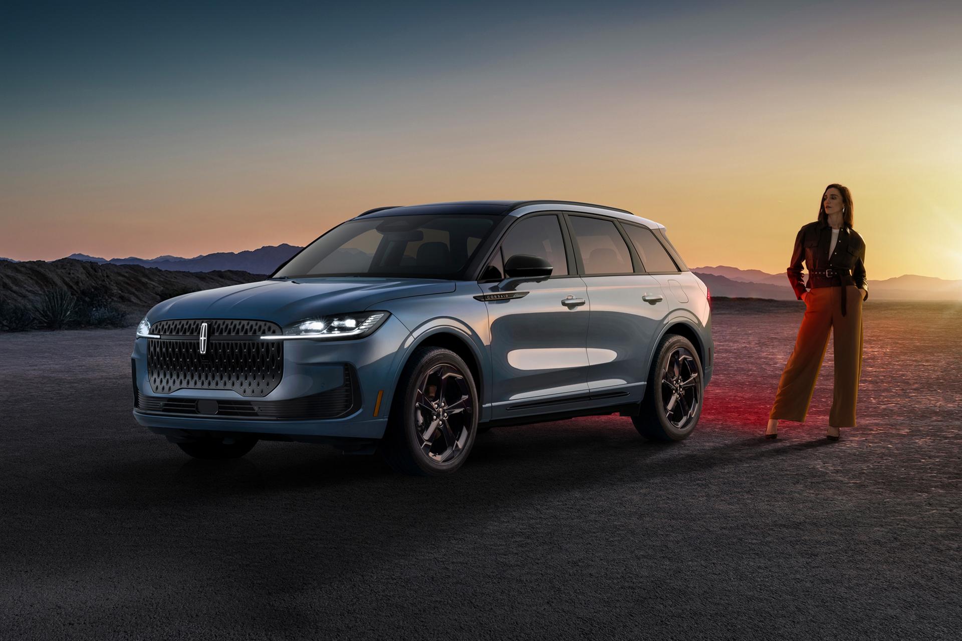 A stylishly dressed woman standing next to a 2027 Lincoln Corsair® Hybrid parked in a dramatic desert landscape.