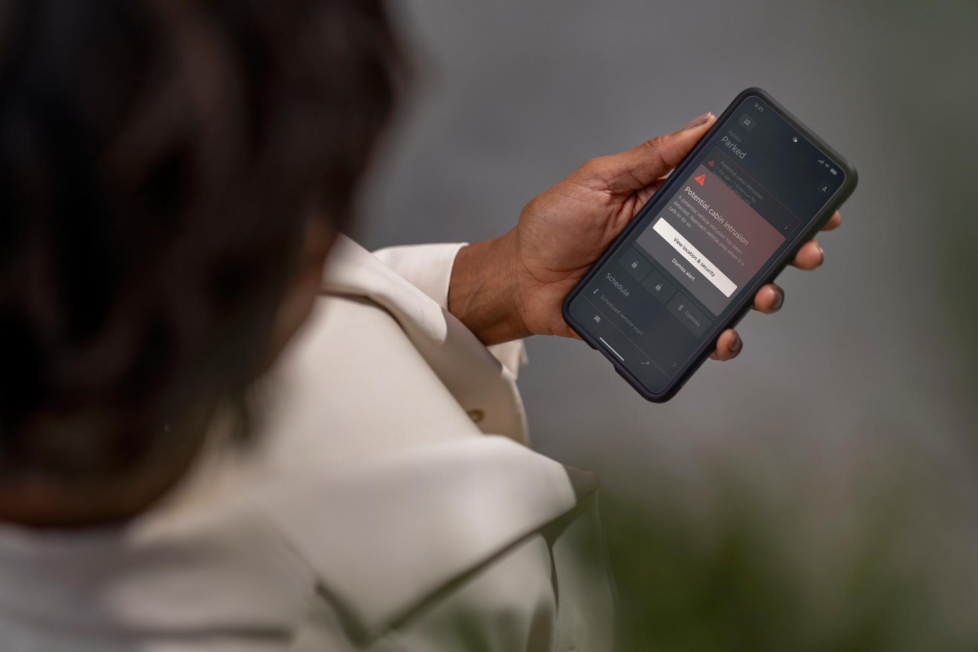 A woman uses her mobile phone to check the security status of her vehicle