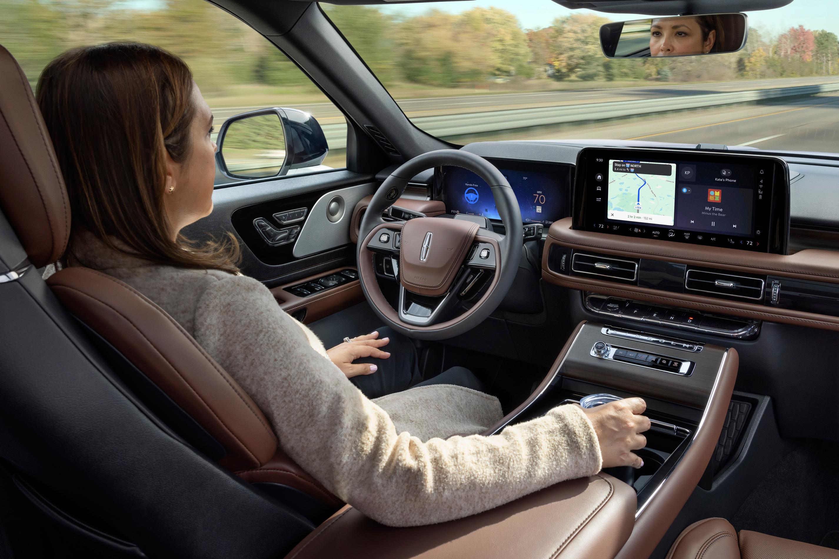 A woman in the driver seat of a Lincoln Nautilus relaxes with hands-free driving technology engaged