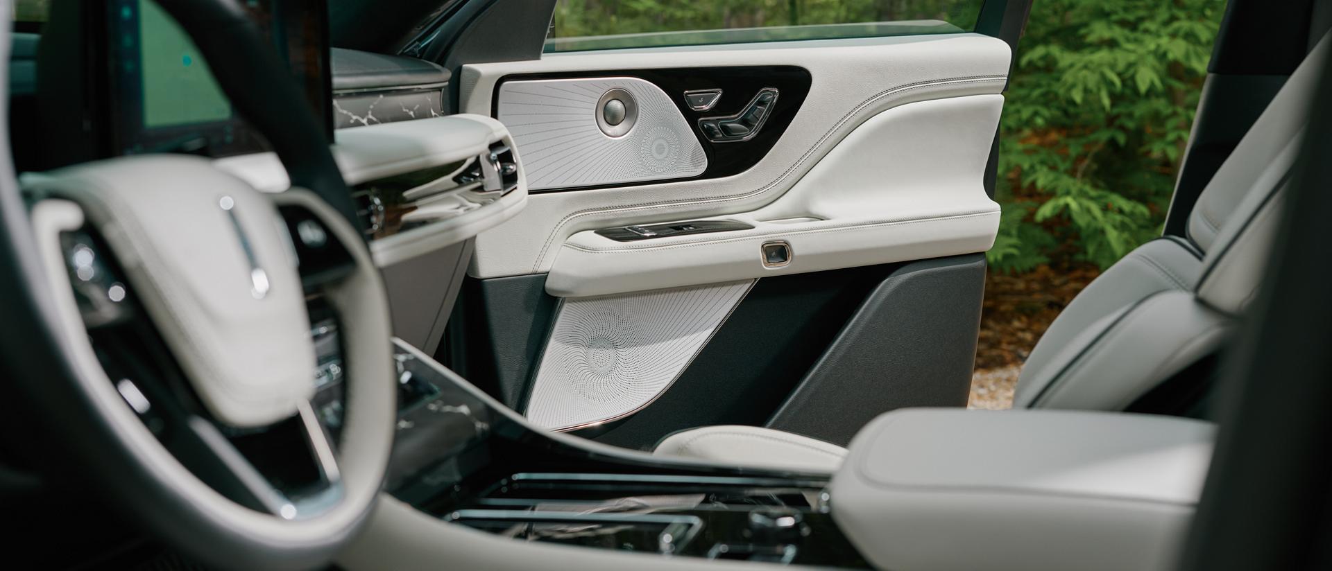 A grouping of audio system speakers in the front passenger door of a 2027 Lincoln Aviator®