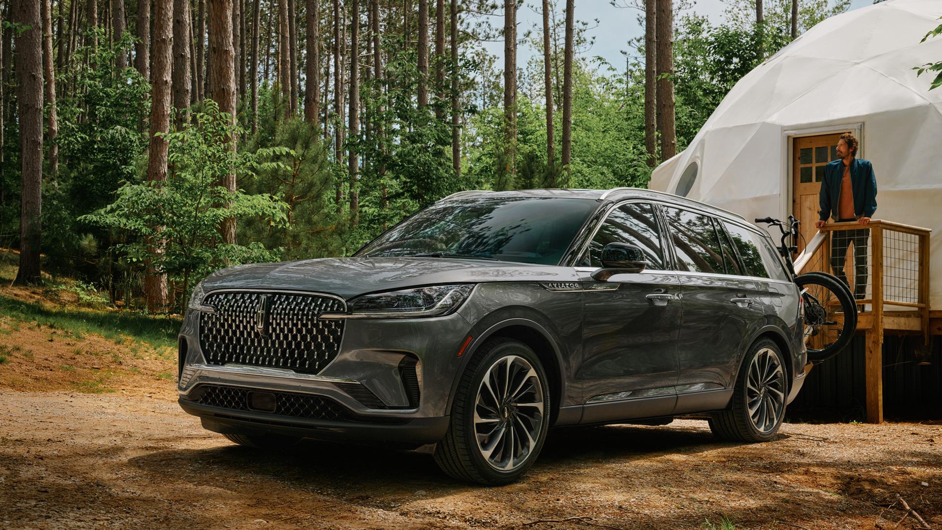 A 2027 Lincoln Aviator SUV is parked next to a luxurious glamping site
