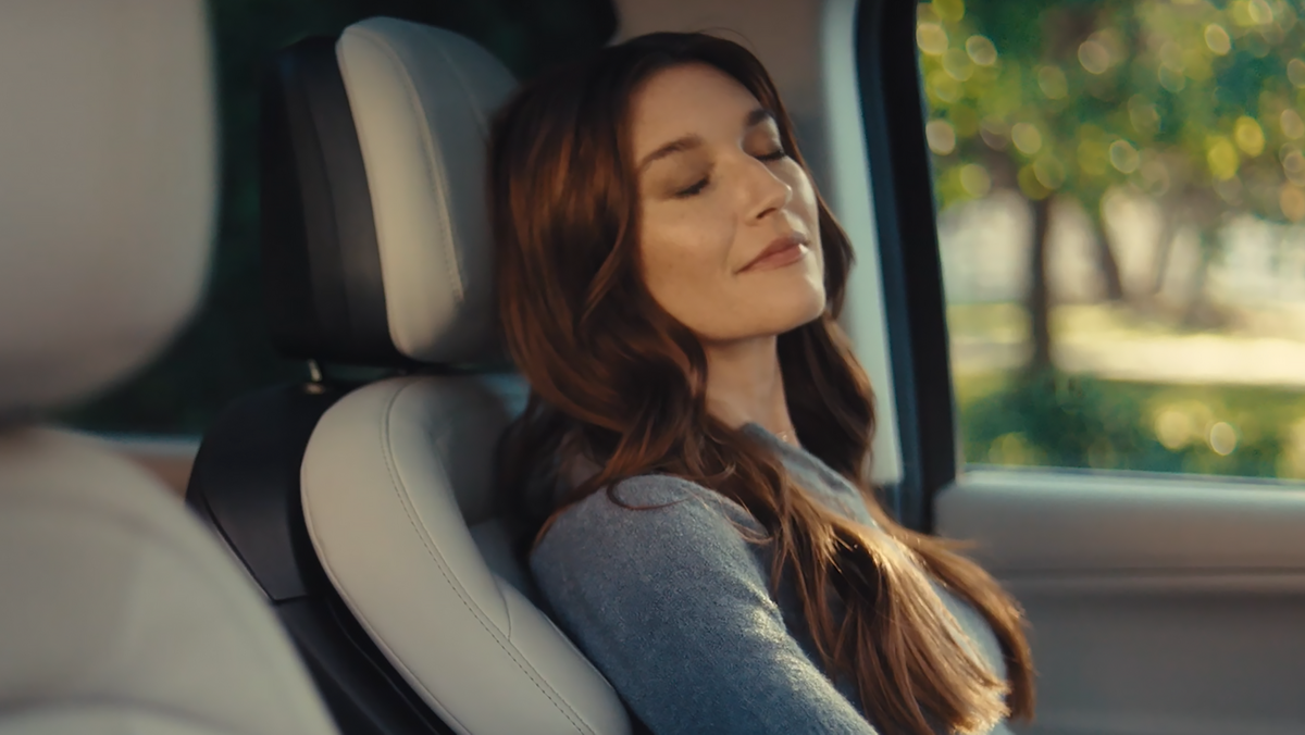 Woman relaxing with closed eyes in a Lincoln seat with massage zone indicators highlighted.
