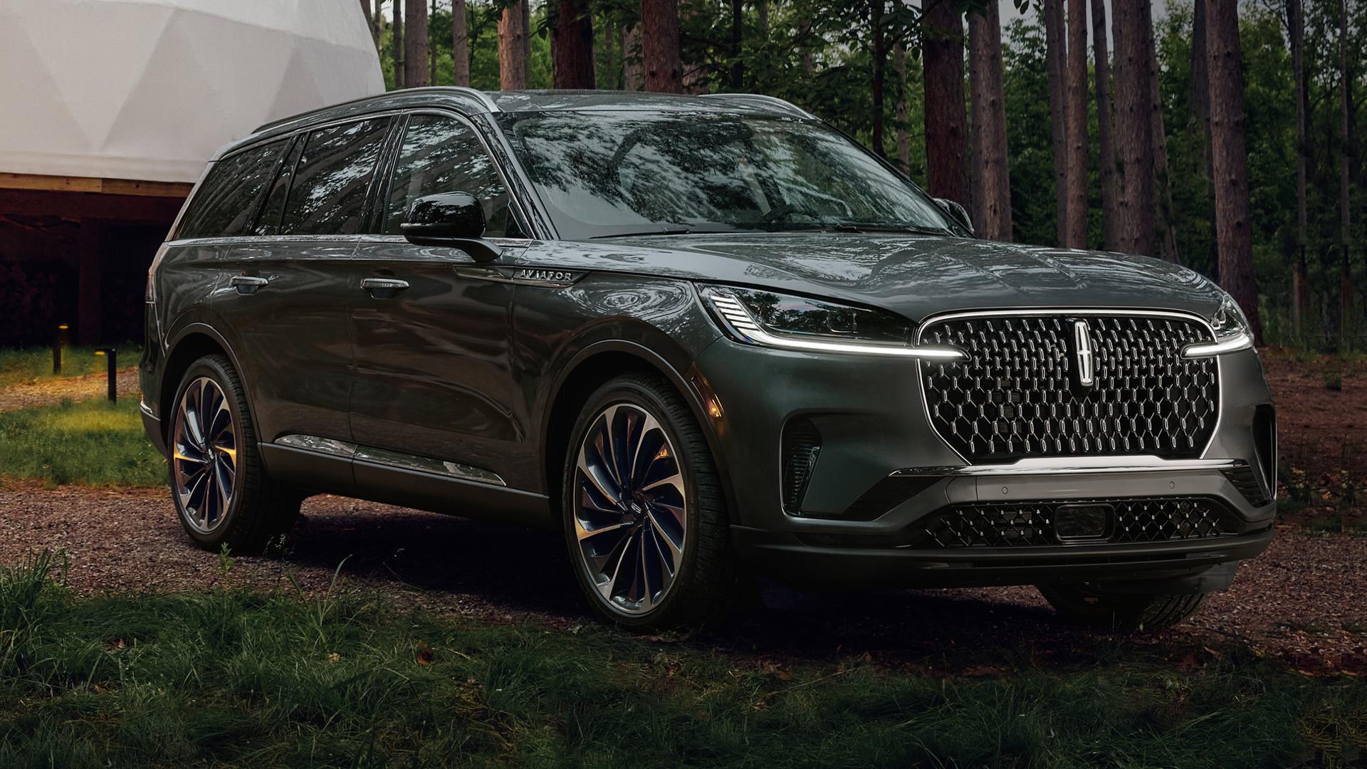 A 2027 Lincoln Aviator with its headlamps illuminated is being driven on a gravel road