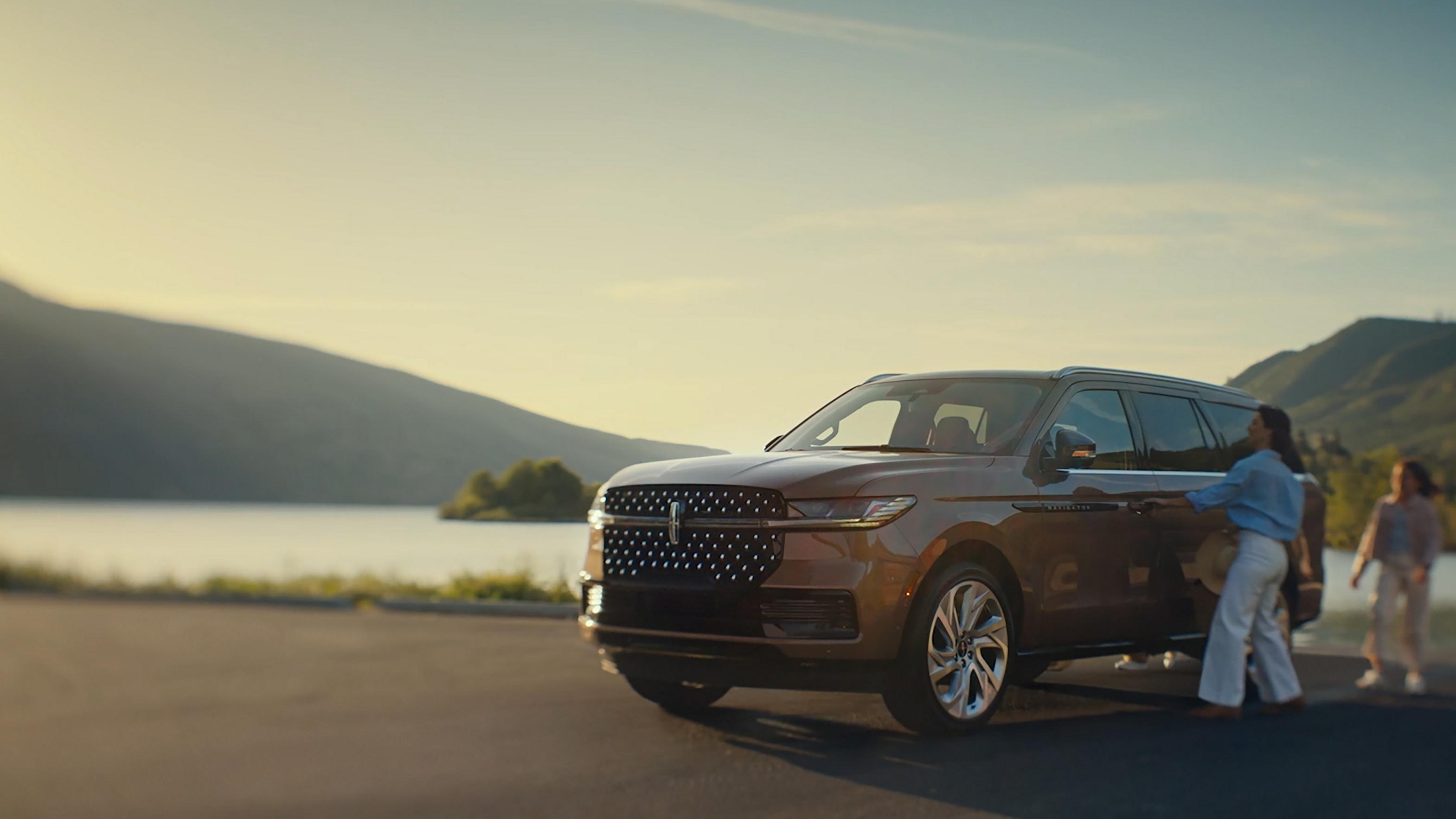 A family approaches a 2026 Lincoln Black Label Navigator® and the Embrace lighting sequence begins