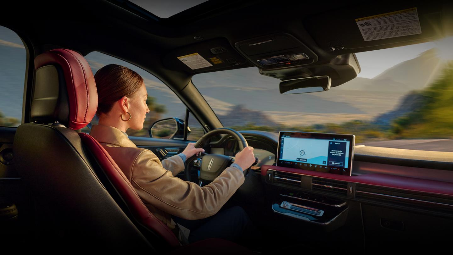 A woman driving a Lincoln vehicle.